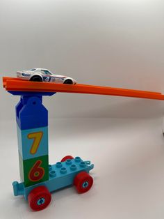 a toy truck pulling a lego car on top of it's back wheels with an orange handle