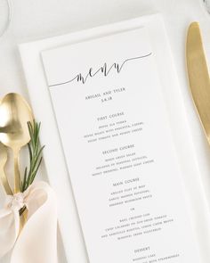 a white menu card on top of a table with gold utensils