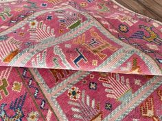 a pink rug with an intricate design on the top and bottom, sitting on a wooden floor