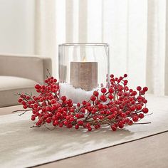 a table with a candle and some red berries on it