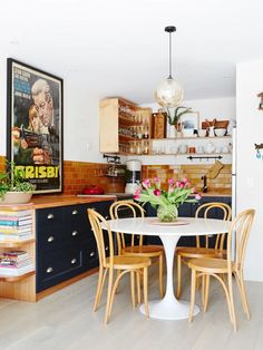 a dining room table with four chairs and a poster on the wall in the background