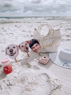 two dogs are sitting in the sand next to hats and other items on the beach