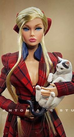 a barbie doll holding a white cat and wearing a red plaid coat with blue eyes