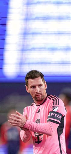 a soccer player in pink is holding his hands out