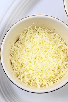 a white bowl filled with cheese on top of a table