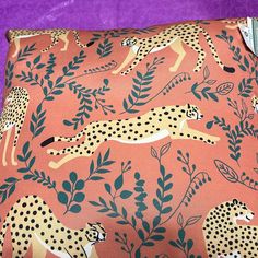 a pink pillow with cheetah and leaves on it, against a purple background