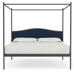 an iron bed frame with white sheets and blue headboard, viewed from the side