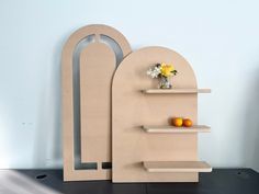 a shelf with some fruit on top of it next to a vase filled with flowers