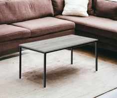 a living room with a couch, coffee table and rug on the floor in front of it