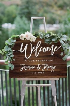 a welcome sign with greenery and flowers on it is displayed in front of a balcony