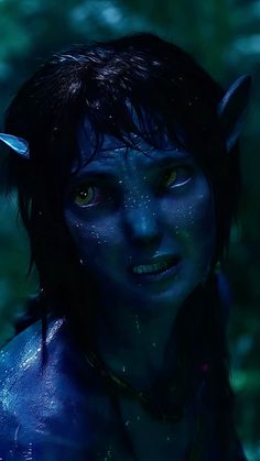 a woman with blue paint on her face and horns in the dark, staring at the camera