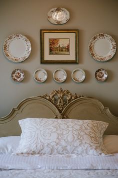 a white bed topped with lots of plates on top of it's headboard