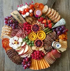 a platter filled with lots of different types of fruit and cheese on top of a wooden table