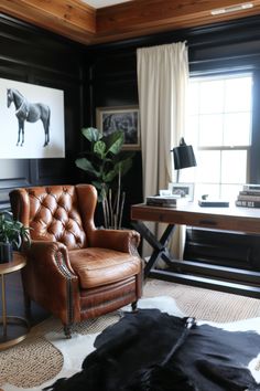 a leather chair sitting in front of a window next to a cowhide rug on the floor