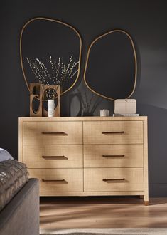 a dresser with two mirrors on top of it and vases in front of it