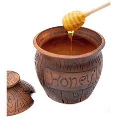 a honey jar with a wooden spoon pouring honey into it