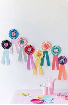 a table topped with lots of colorful paper flowers next to plates and utensils