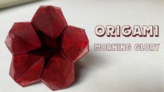 a red origami flower sitting on top of a white surface with the words, organic morning glory