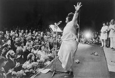 a woman standing on top of a stage in front of a large group of people