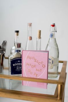 a table topped with bottles and glasses on top of a metal tray next to a mirror