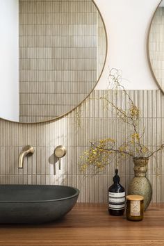 a bathroom with two round mirrors on the wall and a vase filled with flowers next to it