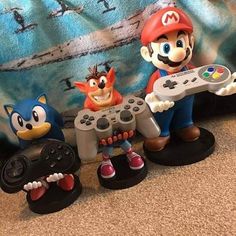 three figurines of mario and sonic the hedgehog holding video game controllers