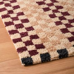 an area rug with black and white squares on top of wooden floor next to wood flooring