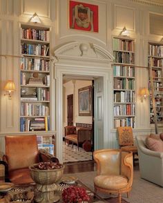 a living room filled with furniture and bookshelves next to a doorway that leads into a library