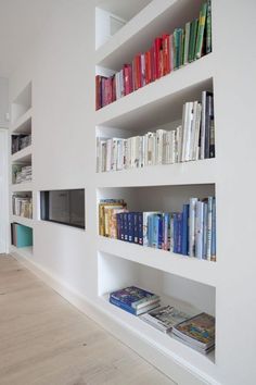 the books are lined up on the white shelves