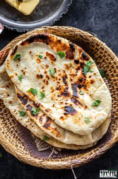 three flat breads in a wicker basket with butter and parsley on the side