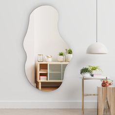 a mirror hanging on the wall next to a table with plants and potted plants