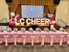 a long table with balloons and flowers on it in front of a large projection screen