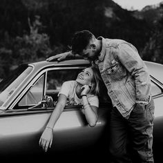 a man and woman leaning on the hood of a car