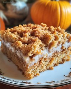 a piece of cake sitting on top of a white plate next to two pumpkins