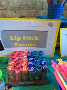 a table topped with lots of different colored cups and straws next to a sign that says lip stick tasers