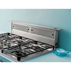 a stainless steel stove top with four burners and two glass bowls on the counter