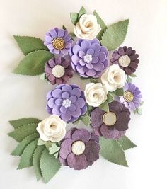 purple and white flowers with green leaves are arranged on a white surface in the shape of a circle