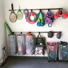 there are many bags and tennis rackets hanging on the wall