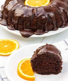 a bundt cake with chocolate frosting and sliced oranges on the plate next to it