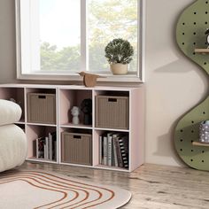 a living room with bookshelves and baskets on the floor next to a window