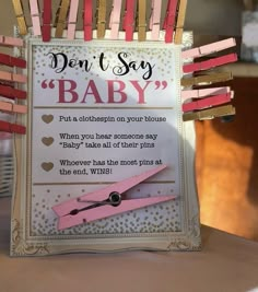 a sign that says don't say baby with clothes pins attached to it and scissors in the middle