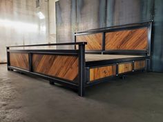 a bed frame made out of wood and metal with drawers on the bottom side, sitting in an empty room