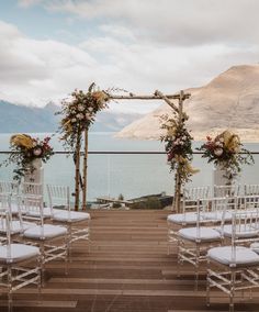 an outdoor ceremony set up with white chairs and flowers