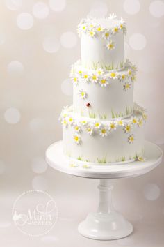 a three tiered cake with daisies on it