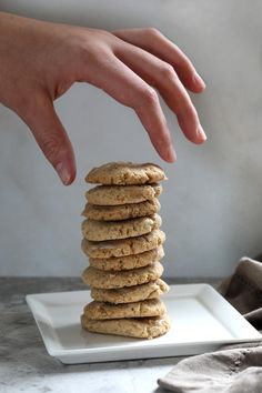 a hand reaching for a stack of cookies on a plate