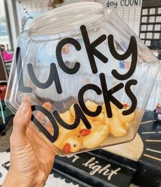 a person holding up a plastic container with lucky ducks in it that says lucky ducks