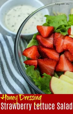 a salad with strawberries and apples is shown in a glass bowl next to dressing