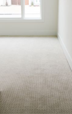 an empty room with a window and carpet