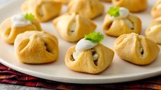 several small pastries on a white plate with green garnishes and parsley