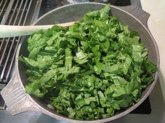 a pan filled with green leafy vegetables on top of a stove